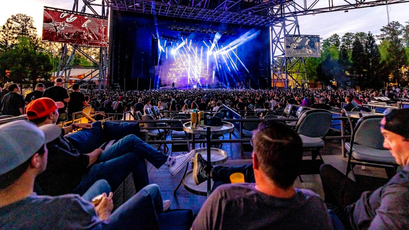 A group of fans sitting at a table in a VIP Box seat watching a concert