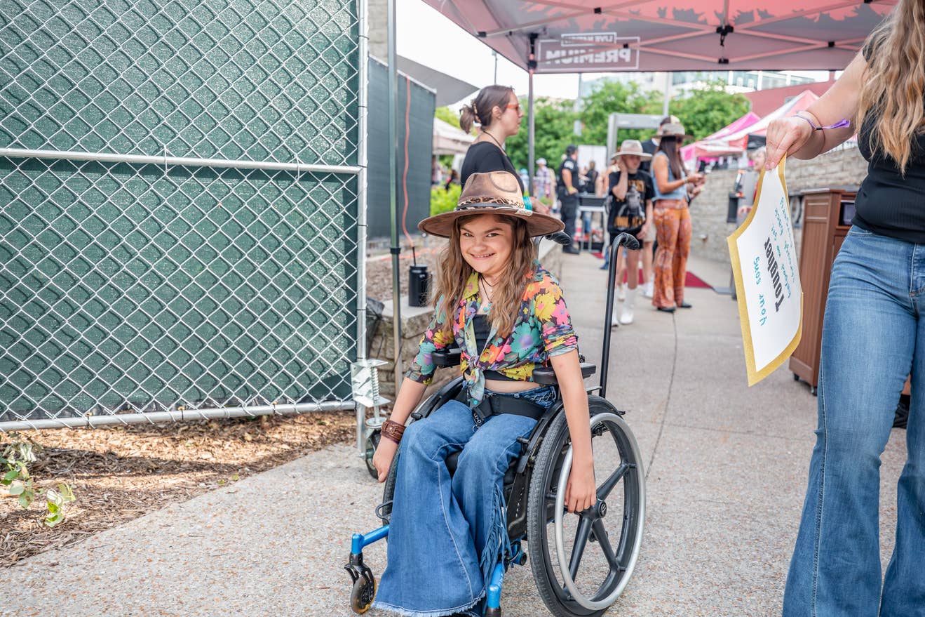 A photo of a young girl in a wheelchair entering the venue.